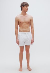 Λευκά σορτς κολύμβησης με ελαστική μέση και κορδόνι, κατασκευασμένα από λείο, ελαφρύ υλικό. Χωρίς ορατά σχέδια ή διακοσμητικά στοιχεία.