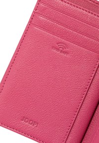 Roza usnjena torbica za kartice z teksturirano površino, ki vsebuje več rež za kartice in odtisnjeno logo. Vključuje tudi zaščitno podrobnost RFID.