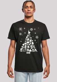 Černé tričko s krátkým rukávem, které zobrazuje bílé grafické designy postav ze Star Wars uspořádaných do tvaru vánočního stromečku se sněhovými vločkami a hvězdami.