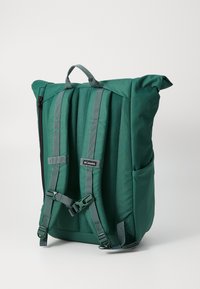 Sac à dos vert avec des bretelles ajustables, un rabat enroulable et des détails en maille. Il dispose de poches latérales et d'une fermeture éclair pour un rangement sécurisé.
