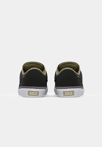 Black sneakers with a canvas upper, flat white sole, greenish interior, and "GLOBE" branding on the heel. Simple design, minimal accents.