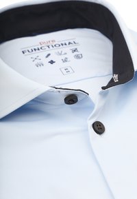Lichtblauwe hem met een zwarte kraag, knoopsluiting en een gemêleerde stof. Het label aan de binnenkant bevat iconen en maatinformatie.