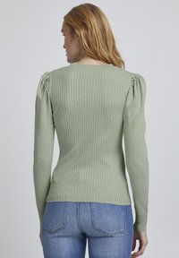 Hellgrüner, gerippter Strickpullover mit langen Ärmeln und puffigem Schulterdetail. Die Passform ist tailliert und am Saum leicht ausgestellt.