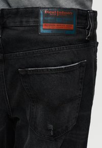 Μαύρο τζιν παντελόνι από τζιν ύφασμα με ορατή ετικέτα. Διαθέτει πίσω τσέπη, ραμμένες λεπτομέρειες και ελαφριά ξεθώριασμα στο ύφασμα.