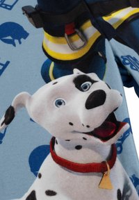 Tessuto in pile stampato con un cane cartone animato con macchie nere e occhi blu, che indossa un collare rosso. Sullo sfondo ci sono icone blu.
