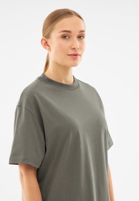 Grijs katoenen T-shirt met een ronde hals, korte mouwen en een ontspannen pasvorm. Gladde textuur zonder zichtbare patronen of afbeeldingen.