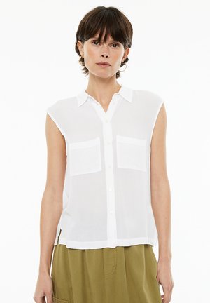 White sleeveless shirt with a collared neckline, two chest pockets, and a button-down front. Made of lightweight, sheer fabric.
