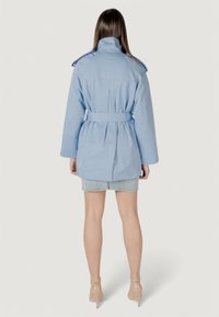 Trench coat azzurro chiaro con vita regolabile, spalline e pieghe posteriori. Presenta maniche lunghe e una vestibilità comoda, realizzato in tessuto per abbigliamento esterno.