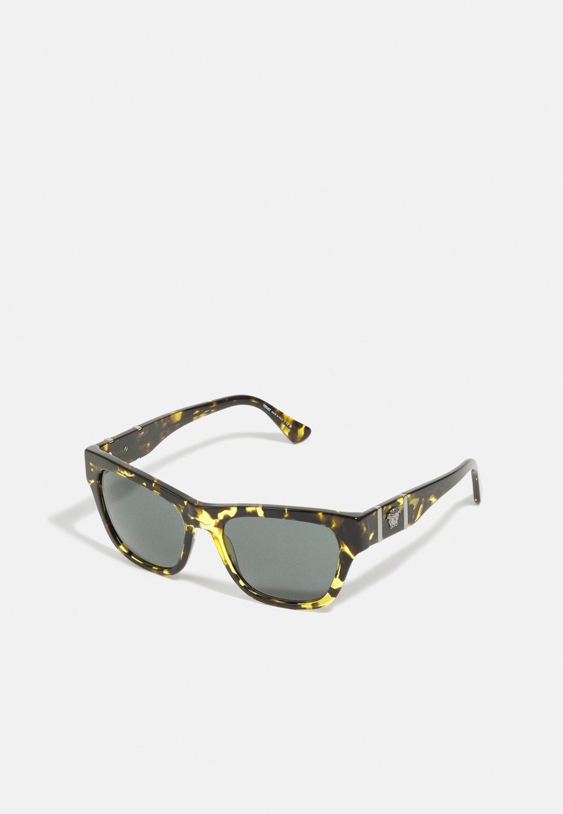 Ochelari de soare cu rame tortoise, în formă rectangulară și cu lentile verzi. Accente distinctive de galben pe ramă. Logo din metal pe tâmplă.