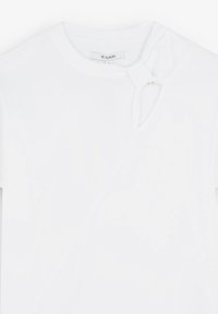 Hvid bomulds T-shirt med en knude detalje ved skulderen og en sideskæring. Korte ærmer og rund halsudskæring. Glat tekstur.