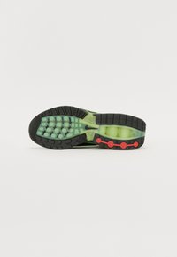 Green and black sneaker sole with a textured rubber finish, featuring visible cushioning, red accents, and a patterned tread design.