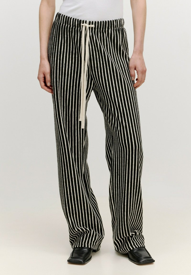 Gestreepte zwart-witte broek met een trekkoord in de taille, losse pasvorm en zachte textuur, met verticale lijnen en aangebrachte randen.