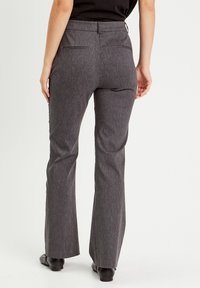 Pantalons évasés gris en tissu texturé. Comprend deux poches arrière et une taille cintrée. Des lignes épurées créent une silhouette ajustée.