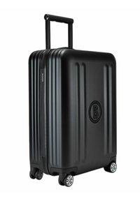 Zwarte harde koffer met verticale ribbels, intrekbare handgreep, vier wielen en een circulair logo. Getextureerde afwerking voor grip.