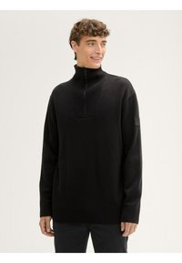 Schwarzer Pullover aus Strickstoff, mit einem hohen Kragen und einem halben Reißverschluss, gerippten Bündchen und einer Schulterpasse.