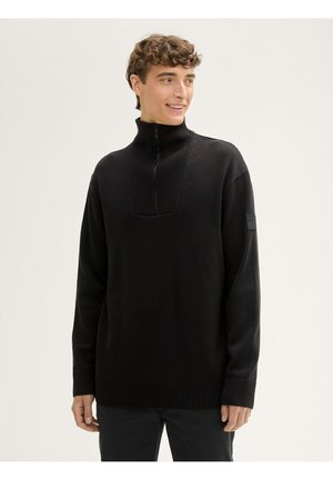 Schwarzer Pullover aus Strickstoff, mit einem hohen Kragen und einem halben Reißverschluss, gerippten Bündchen und einer Schulterpasse.