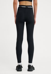 Svarta leggings med hög midja som har en vit logotyp. Slät, elastisk material med en åtsittande design och minimal detaljer.
