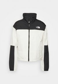 Krótkia kurtka z wysokim kołnierzem, z kolorowym blokiem w czerni i bieli, z zapięciem na zamek błyskawiczny oraz logo na lewej piersi.