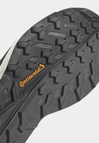 Schwarze Gummisohle mit tiefen Profil und strukturiertem Oberflächen, mit einem orangefarbenen "Continental"-Logo in der Mitte.