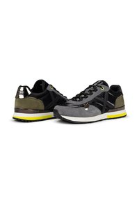Zapatillas deportivas en ante y cuero negro, gris y verde oliva, con un acento amarillo en la suela y detalles de hardware brillante.