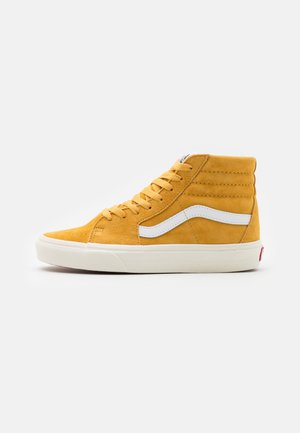 Gelber High-Top-Sneaker mit weißem Seitenstreifen, weißer Sohle und Schnürsenkeln auf schlichtem hellem Hintergrund, von der Außenseite aus gesehen.