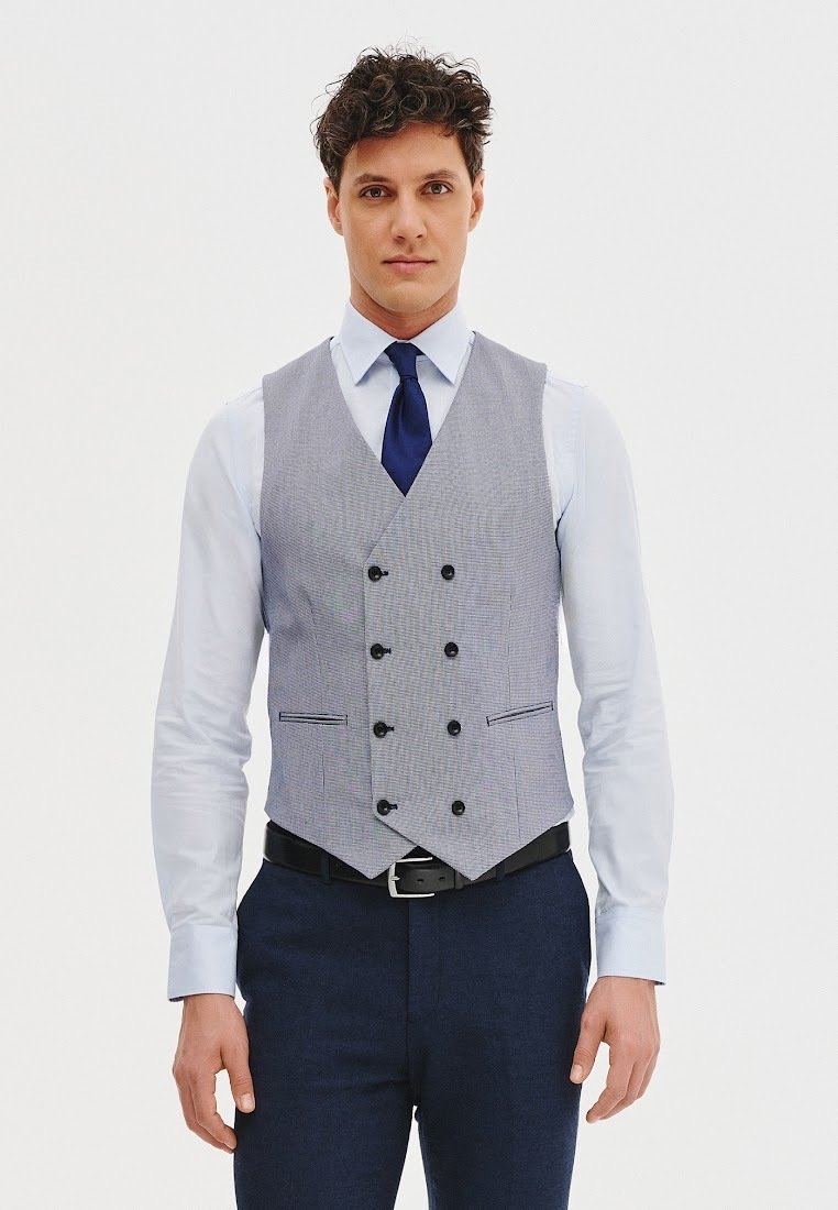 Szary kamizelka w paski z sześcioma guzikami, czarnymi akcentami i dwoma kieszeniami z przodu. Nosi się ją na białej koszuli i zestawia z niebieską krawatem.