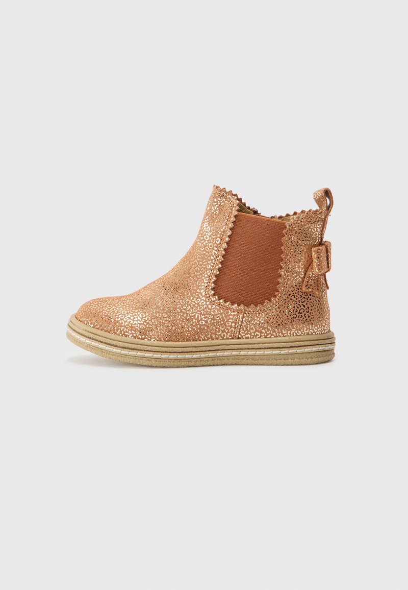 Botines de bronce con glitter, paneles laterales elásticos, bordes ondulados y una pequeña lengüeta en la parte trasera. Superficie texturizada y suela de goma beige.