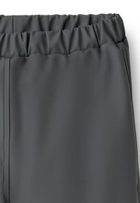 Pelēkas sporta bikses ar elastīgu jostu un gludu, teksturētu audumu ar sānu šuvēm, piemērotas sportiskai lietošanai.