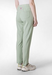 Lichtgroene broek met elastische tailleband en twee achterzakken, met een slim fit en een zachte katoenstructuur. Versierd met een klein roze label.