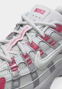 Λευκό και ροζ αθλητικό παπούτσι Nike με πλέγμα ύφασμα, λεπτομερή κορδόνια και ετικέτα «III Bowerman Series» στη γλώσσα.