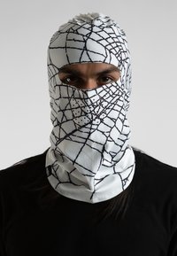 Balaclava blanca con patrón de telaraña negra, que presenta agujeros de ventilación de malla, diseño ajustado y textura suave. Llevada sobre ropa oscura.