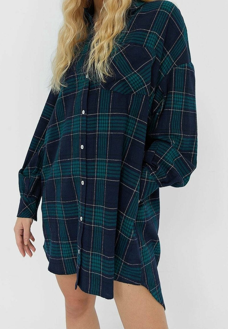 Marinblå och grön rutigt flanellskjorta, långa ärmar, knappframsidan, två bröstfickor, avslappnad passform, sidoflikar vid nederkanten.