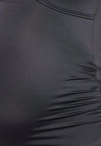 Material de suită negru, cu o textură netedă, prezentând detalii subtile de adunare pe lateral și un design cu guler rotunjit.