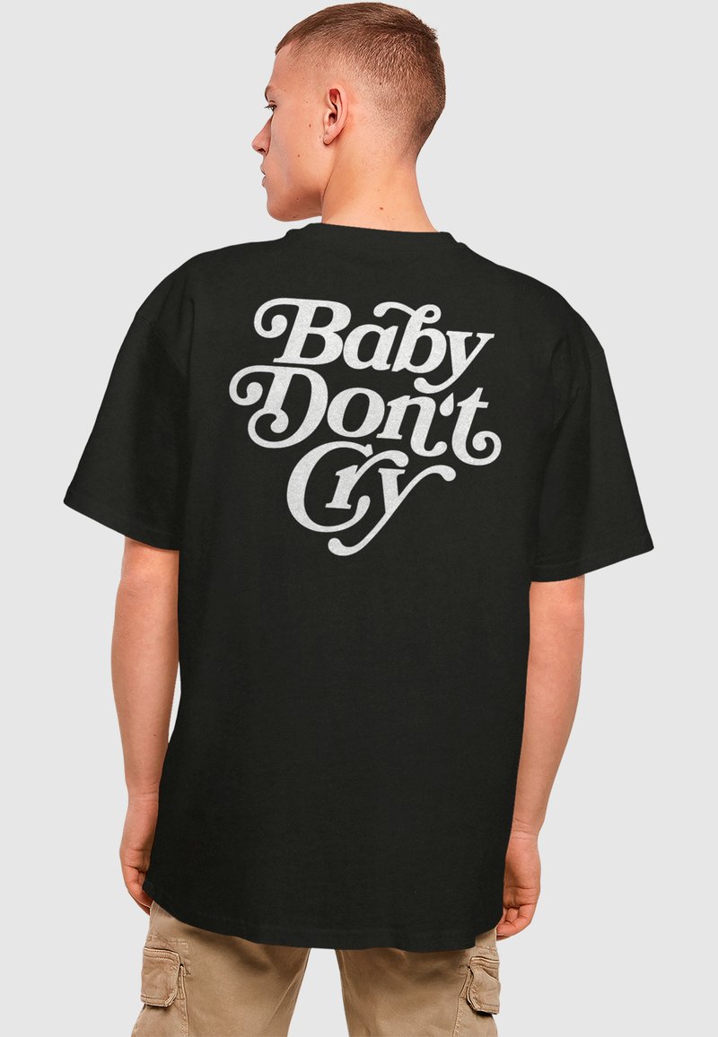 Juodas medvilninis marškinėlis su drąsia balta stilizuota užrašu ant nugaros "Baby Don't Cry." Trumpomis rankovėmis, laisvo kirpimo.
