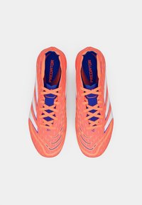 Scarpette da calcio arancioni brillanti con accenti bianchi, tomaia testurizzata e interno blu. Presentano un design con lacci e un marchio audace sulla linguetta.