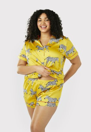 Yellow satin pajama set featuring black and white zebra patterns; short-sleeve button-up top and matching shorts with an elastic waistband.