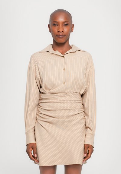 Robe rayée beige avec un col, des manches longues et des détails de taille froncée, fabriquée dans un tissu doux et léger.