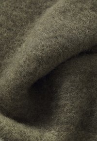 Tissu en laine vert olive, texture douce avec une finition duveteuse. Le matériau est épais et chaud, avec un léger éclat.