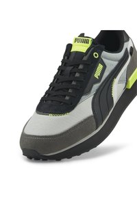 Puma-sneaker med en grå och svart ovandel, i mocka och textilmaterial, gröna detaljer och en tung sula för ökad höjd och komfort.