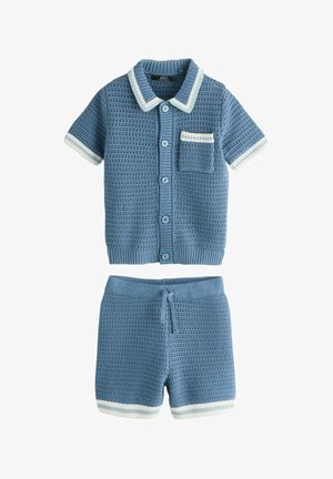 Modrá pletená košeľa s krátkym rukávom, golierom a vreckom, v páre s odpovedajúcimi šortkami so šnúrkou a bielym lemom.
