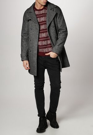 Gray wool peacoat with double-breasted buttons, worn over a maroon, patterned sweater. Black skinny jeans and ankle boots complete the outfit.
