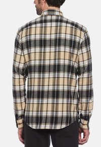 Beige en zwarte geruite flanellen shirt met lange mouwen, knoopmanchetten, gebogen onderkant en subtiele textuur. Achteraanzicht toont het ruitpatroon.