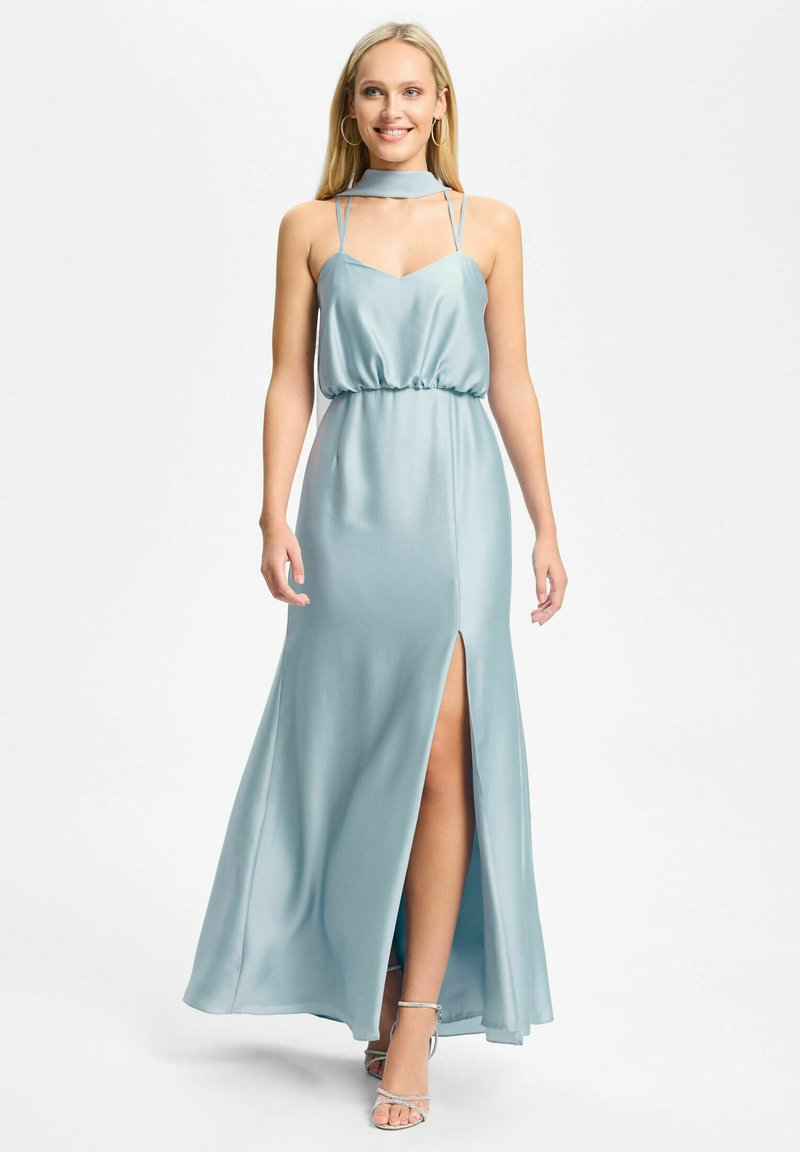Femme portant une robe sans manches en satin bleu clair avec une fente haute et un col ras du cou, associée à des talons argentés à brides.