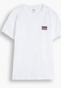 Balts kokvilnas T-krekls ar īsām piedurknēm, uz kura kreisajā krūtīs ir neliels zils, sarkans un melns taisnstūra Levi's logo.
