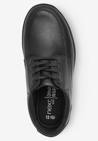 Chaussure en cuir noire avec une texture lisse, bout arrondi, détails cousus et lacets. Taille marquée comme 12 (G) et inclut un soutien orthopédique.