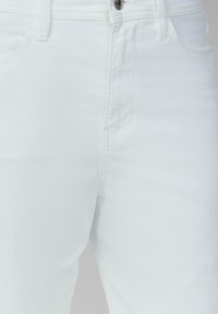 Weiße Jeans aus Denim mit klassischen Design, fünf Taschen sowie einem Frontknopf und Reißverschluss. Der Stoff ist glatt und leicht.