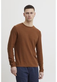 Brown long-sleeve knit shirt with a crew neckline, featuring a textured, ribbed fabric and a lightweight design.
