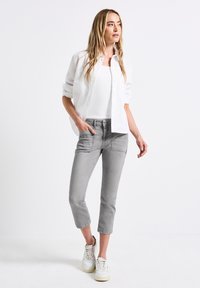 Harmaat slim-fit lyhyet housut, joissa on neljä taskua, yhdistetty valkoiseen toppiin ja valkoiseen nappikauluspaitaan, käytetty valkoisten lenkkareiden kanssa.