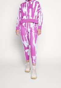 Růžová a bílá vzorovaná mikina s kapucí a zkráceným spodním lemem, spojená s odpovídajícími růžovými legínami s abstraktními vzory.