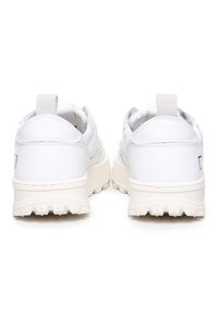 Sneakers bianchi con superiore in rete testurizzata, dettagli in pelle liscia e suola chunky bianca con un pronunciato battistrada seghettato.